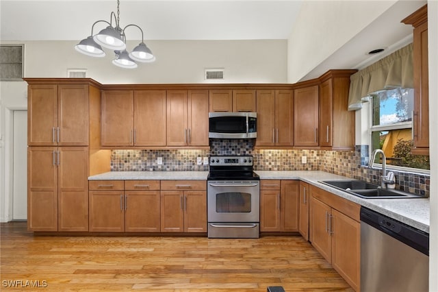 kitchen featuring appliances with stainless steel finishes, decorative light fixtures, decorative backsplash, and light hardwood / wood-style flooring