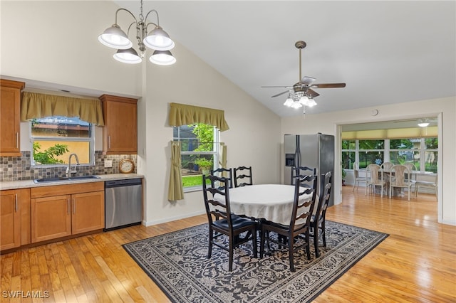 dining space featuring sink, high vaulted ceiling, ceiling fan with notable chandelier, and light wood-type flooring