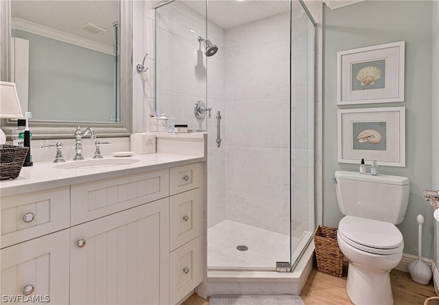 bathroom with toilet, wood finished floors, vanity, ornamental molding, and a stall shower