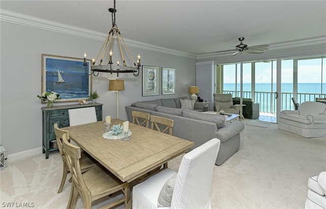 dining space featuring light carpet, a water view, a ceiling fan, baseboards, and ornamental molding