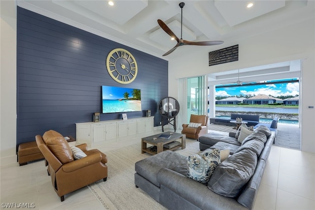 living room featuring beam ceiling, ceiling fan, coffered ceiling, a towering ceiling, and wooden walls