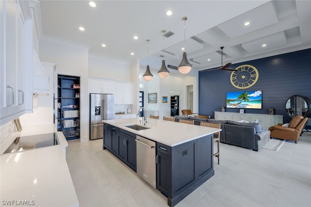 kitchen with appliances with stainless steel finishes, sink, a center island with sink, white cabinets, and hanging light fixtures