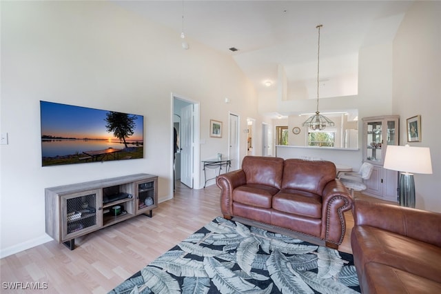 living room featuring high vaulted ceiling, visible vents, light wood-style flooring, and baseboards