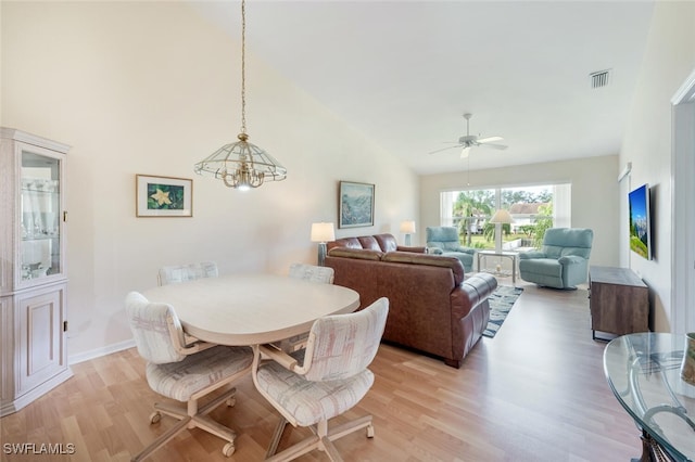 dining room featuring visible vents, baseboards, a ceiling fan, light wood-style floors, and high vaulted ceiling