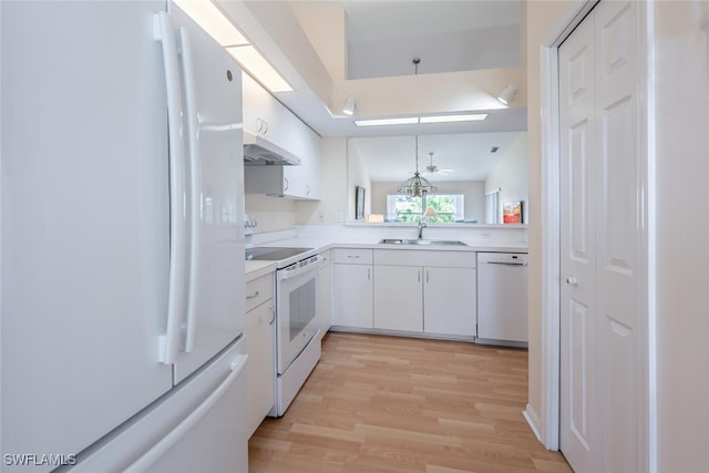 kitchen with white appliances, white cabinets, light countertops, under cabinet range hood, and a sink