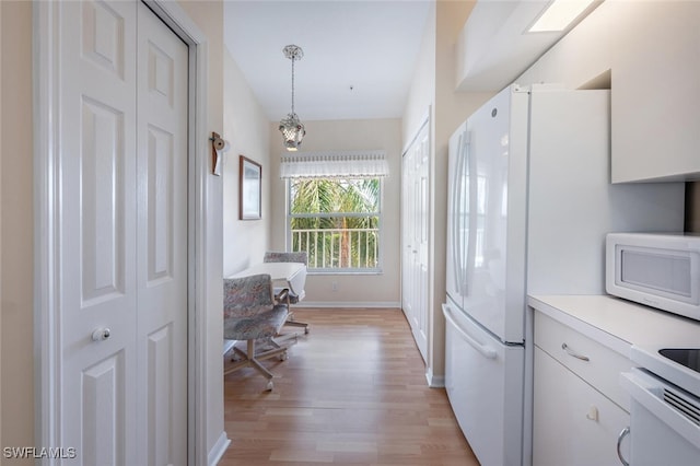 kitchen featuring light wood finished floors, white appliances, baseboards, light countertops, and pendant lighting