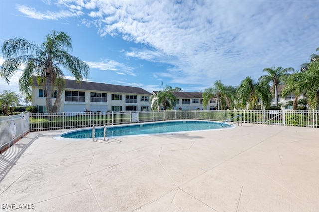 community pool with a patio area and fence