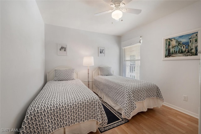 bedroom featuring a ceiling fan, baseboards, and wood finished floors