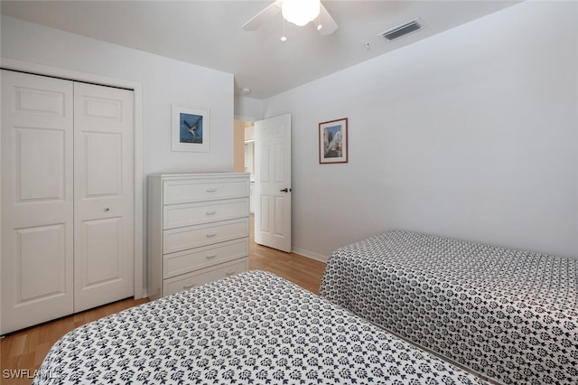 bedroom featuring baseboards, visible vents, ceiling fan, light wood-style floors, and a closet