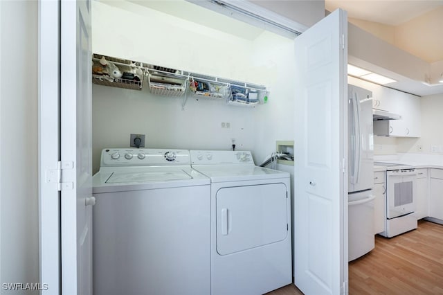 clothes washing area featuring light wood-style flooring, laundry area, and washer and clothes dryer