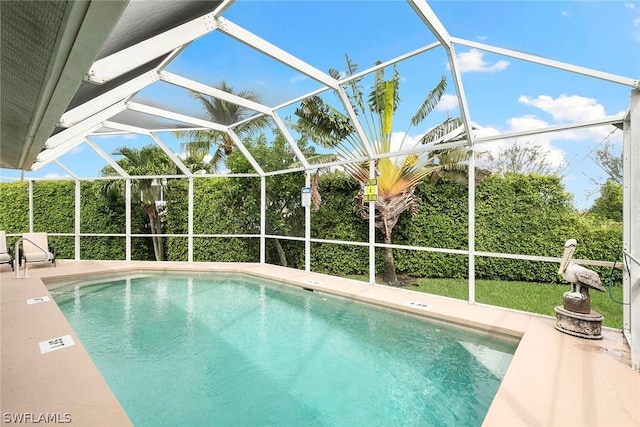 outdoor pool featuring glass enclosure and a patio