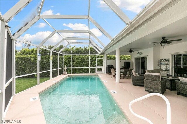 view of swimming pool featuring a patio, a lanai, an outdoor living space, and ceiling fan