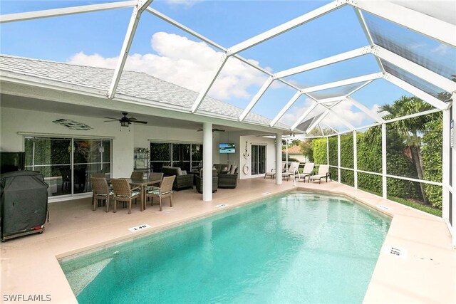 view of pool featuring an outdoor living space, a patio, glass enclosure, and ceiling fan