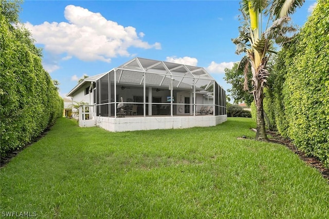 back of house with a lanai and a lawn