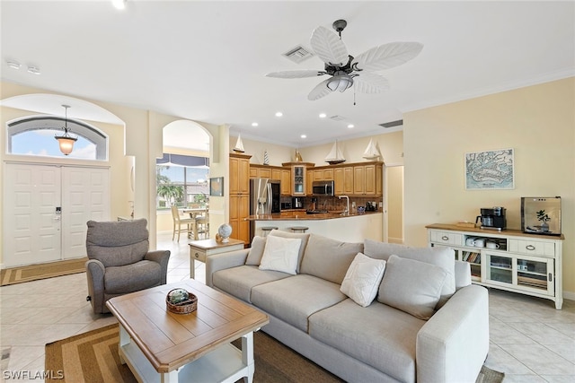 tiled living room with ornamental molding and ceiling fan