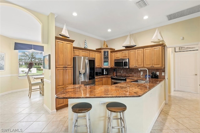 kitchen with dark stone counters, backsplash, stainless steel appliances, sink, and light tile floors