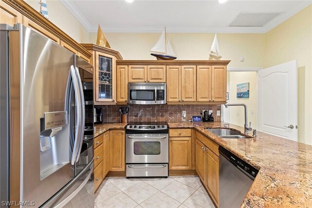 kitchen with tasteful backsplash, stainless steel appliances, light stone counters, light tile floors, and sink