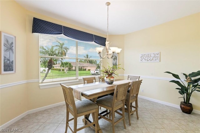 dining area with a notable chandelier, light tile patterned flooring, and baseboards