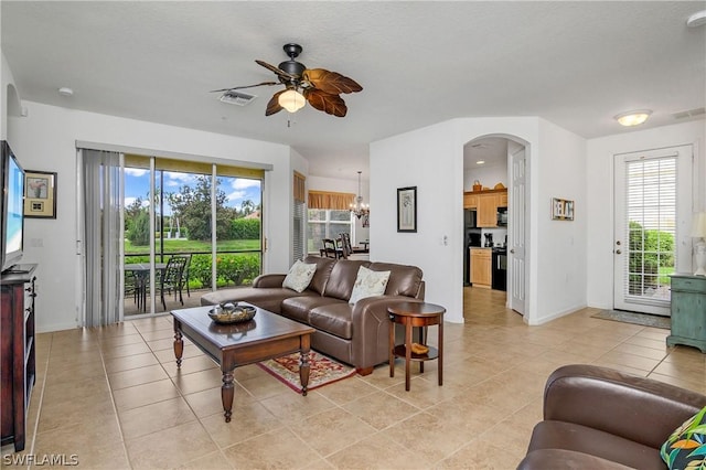 tiled living room featuring ceiling fan with notable chandelier