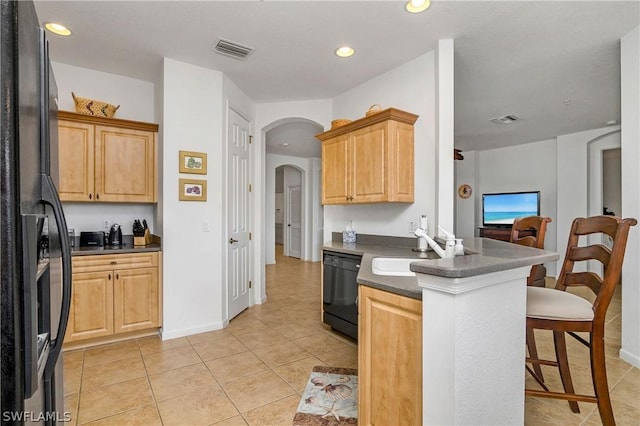 kitchen featuring light tile patterned flooring, light brown cabinetry, black appliances, sink, and kitchen peninsula