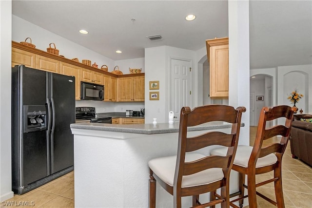 kitchen featuring kitchen peninsula, light tile patterned floors, and black appliances