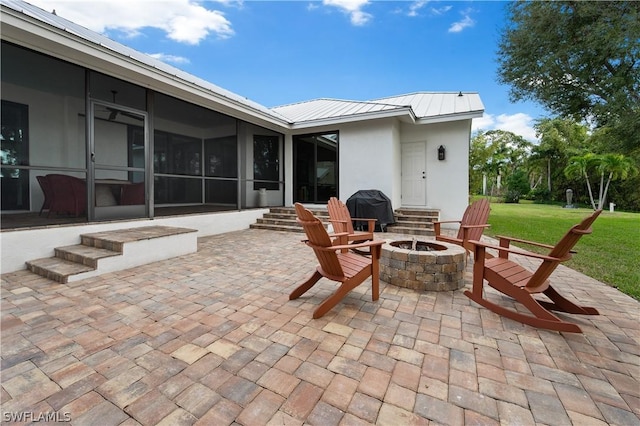 view of patio featuring area for grilling, a sunroom, and an outdoor fire pit