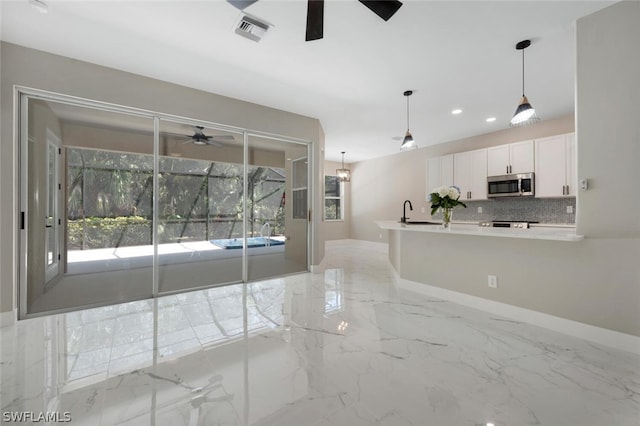 interior space featuring decorative light fixtures, white cabinetry, backsplash, and a wealth of natural light