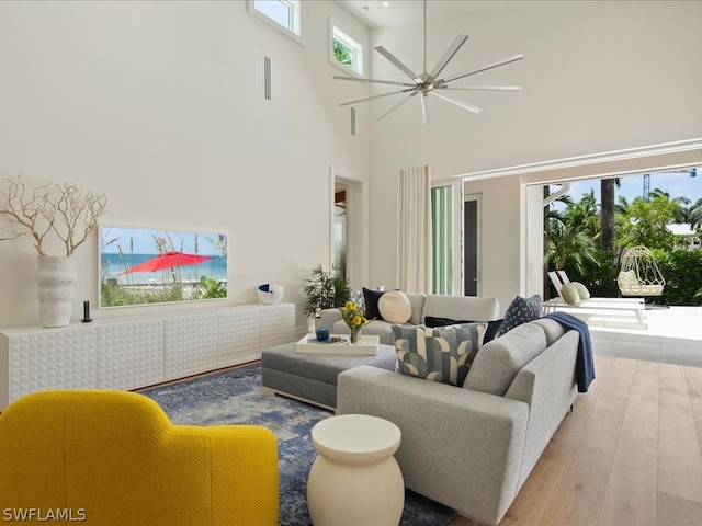 living room featuring ceiling fan, a towering ceiling, and hardwood / wood-style floors