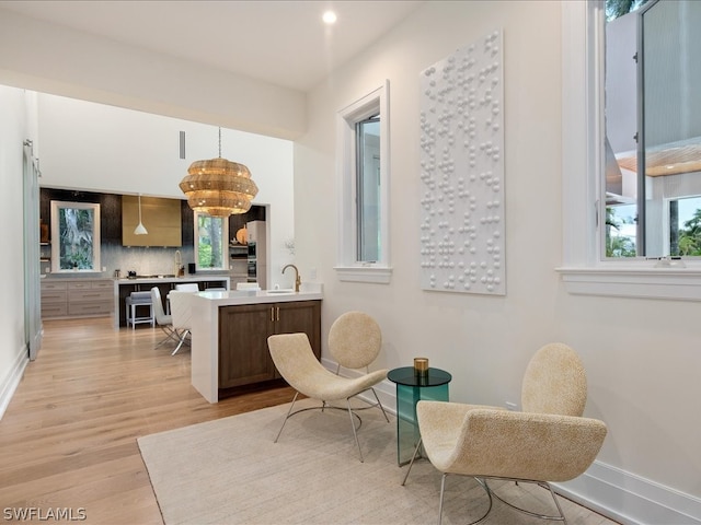 living area with a chandelier, sink, and light wood-type flooring