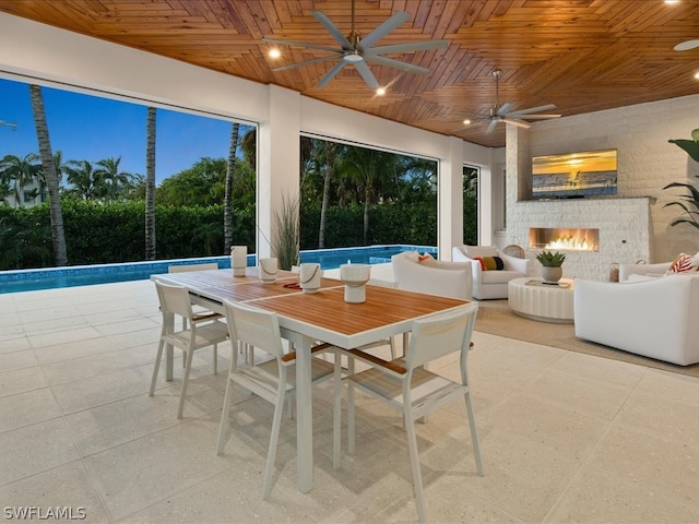 exterior space featuring a stone fireplace, wooden ceiling, and ceiling fan