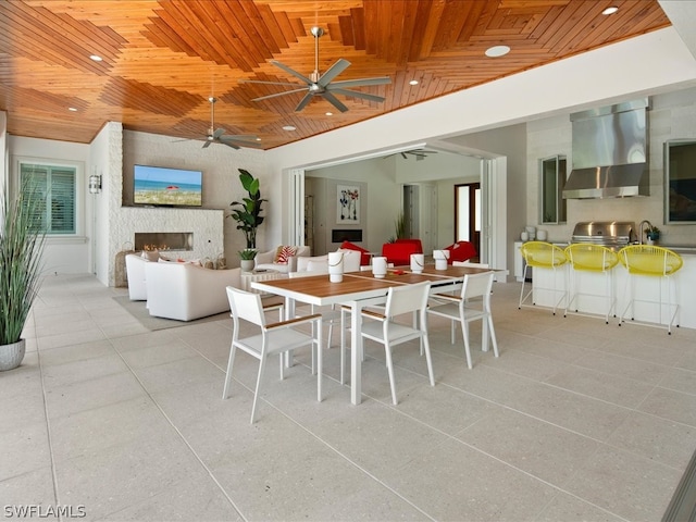 dining area featuring wood ceiling, a fireplace, and ceiling fan