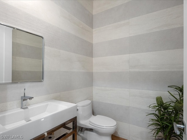 bathroom featuring toilet, vanity, and tile walls