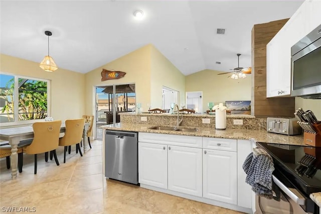 kitchen featuring stainless steel appliances, sink, white cabinets, hanging light fixtures, and lofted ceiling