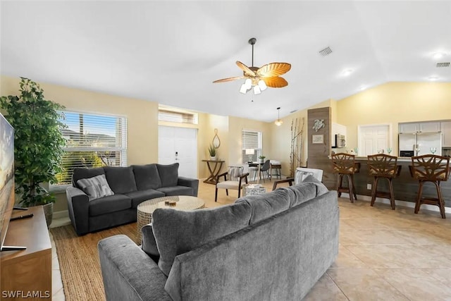 living room with ceiling fan, light tile patterned flooring, and vaulted ceiling