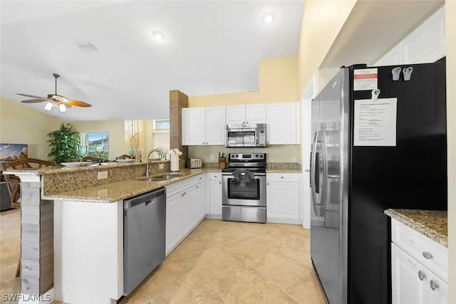 kitchen with kitchen peninsula, appliances with stainless steel finishes, white cabinets, and sink