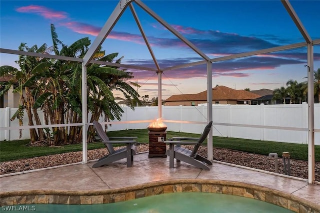 pool at dusk featuring a patio and a lanai