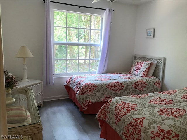 bedroom with ceiling fan, multiple windows, and dark wood-type flooring