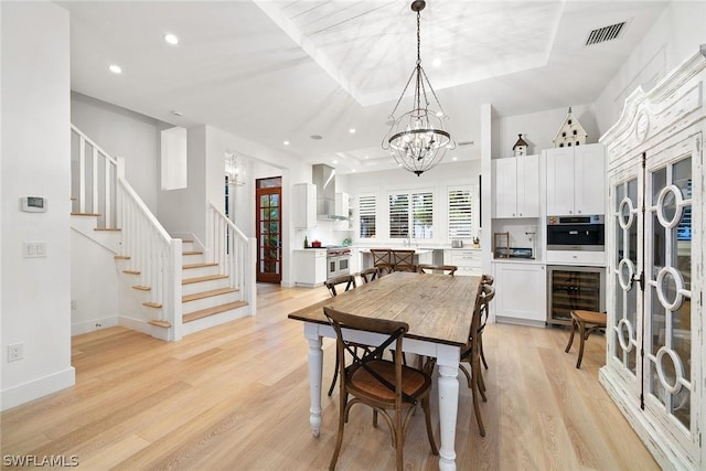 dining space with light wood-type flooring, beverage cooler, and a chandelier