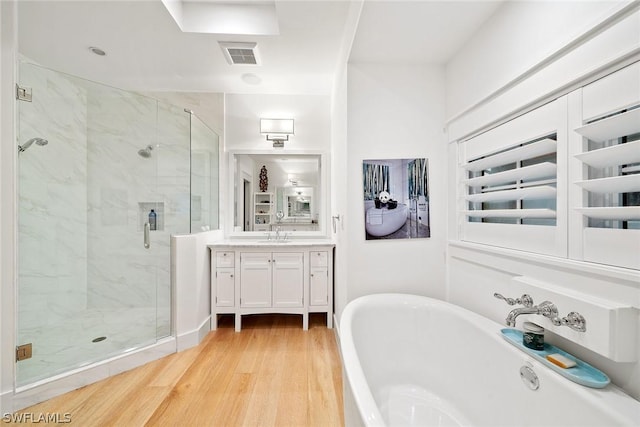 bathroom with wood-type flooring, independent shower and bath, and vanity