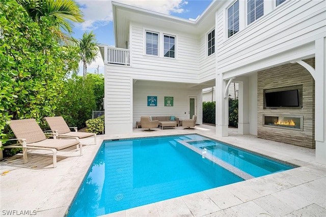 back of house with a patio and an outdoor living space with a fireplace