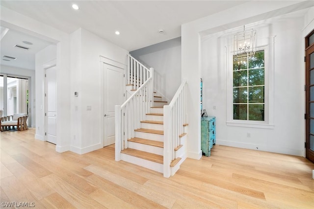 stairs with hardwood / wood-style floors and a notable chandelier