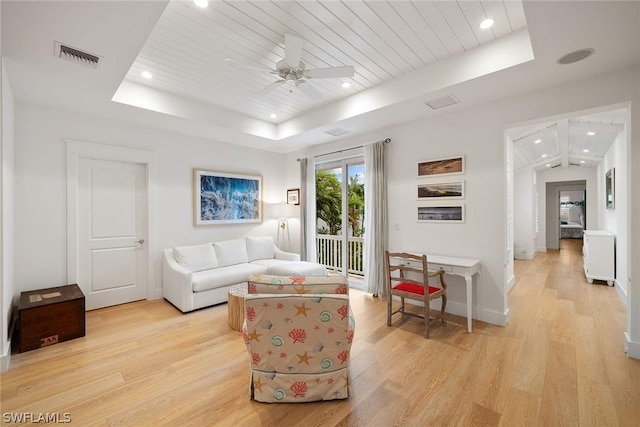 living area featuring light wood-type flooring, wooden ceiling, ceiling fan, and a raised ceiling