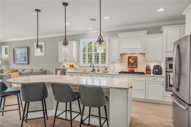 kitchen with white cabinets, a center island, decorative light fixtures, stainless steel fridge, and custom range hood