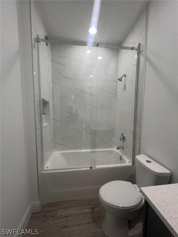 full bathroom with combined bath / shower with glass door, vanity, hardwood / wood-style flooring, and toilet