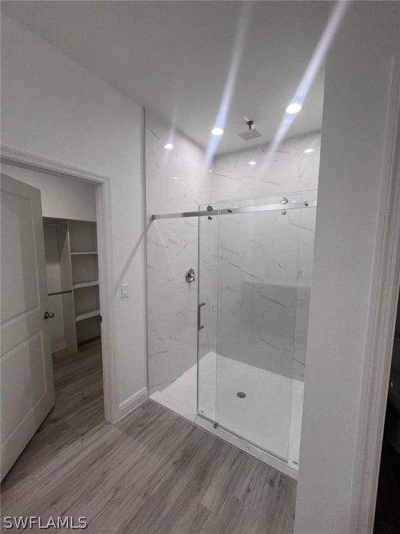 bathroom with wood-type flooring and an enclosed shower