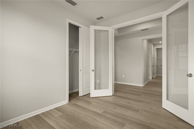 unfurnished bedroom with a closet, visible vents, baseboards, and wood finished floors