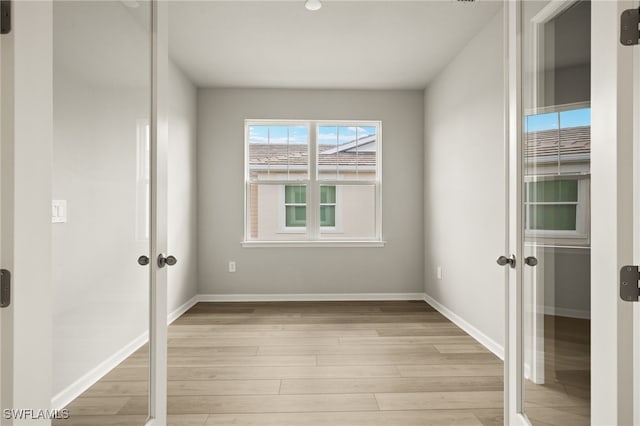 unfurnished room featuring light wood-style flooring, french doors, and baseboards