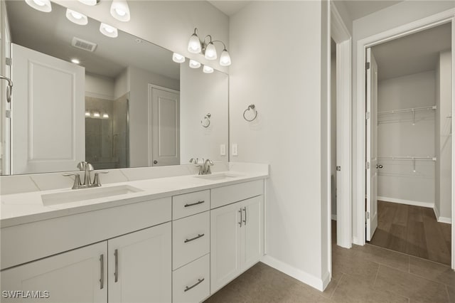 bathroom featuring a shower stall, a spacious closet, double vanity, and a sink