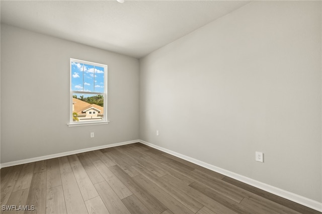 empty room featuring dark wood-type flooring and baseboards