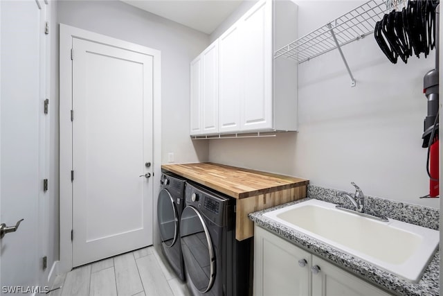 laundry area featuring cabinets, washer and clothes dryer, and sink